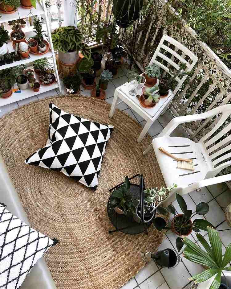balkon w miejskiej dżungli z dużą ilością roślin i dywanem sizalowym