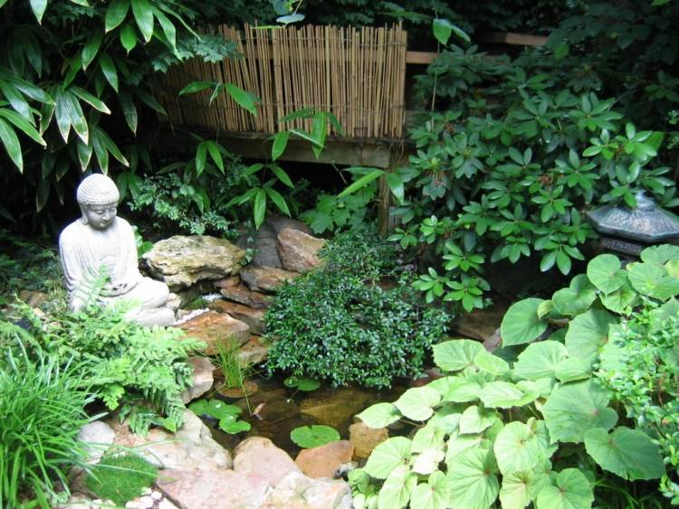 mały staw w ogrodzie Feng Shui z kamiennymi figurami na brzegu Feng Shui ogrodowe figurki ze stawu i lilii wodnej