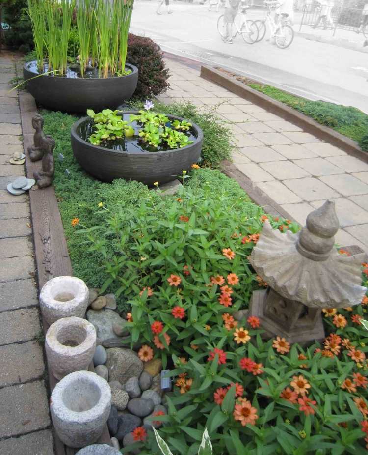 Mini staw w wiadrze z roślinami wodnymi i figurami Buddy wykonanymi z kamienia feng-shui-projektowanie-ogrodu-mini-stawu-buddy-kamienne-figurki